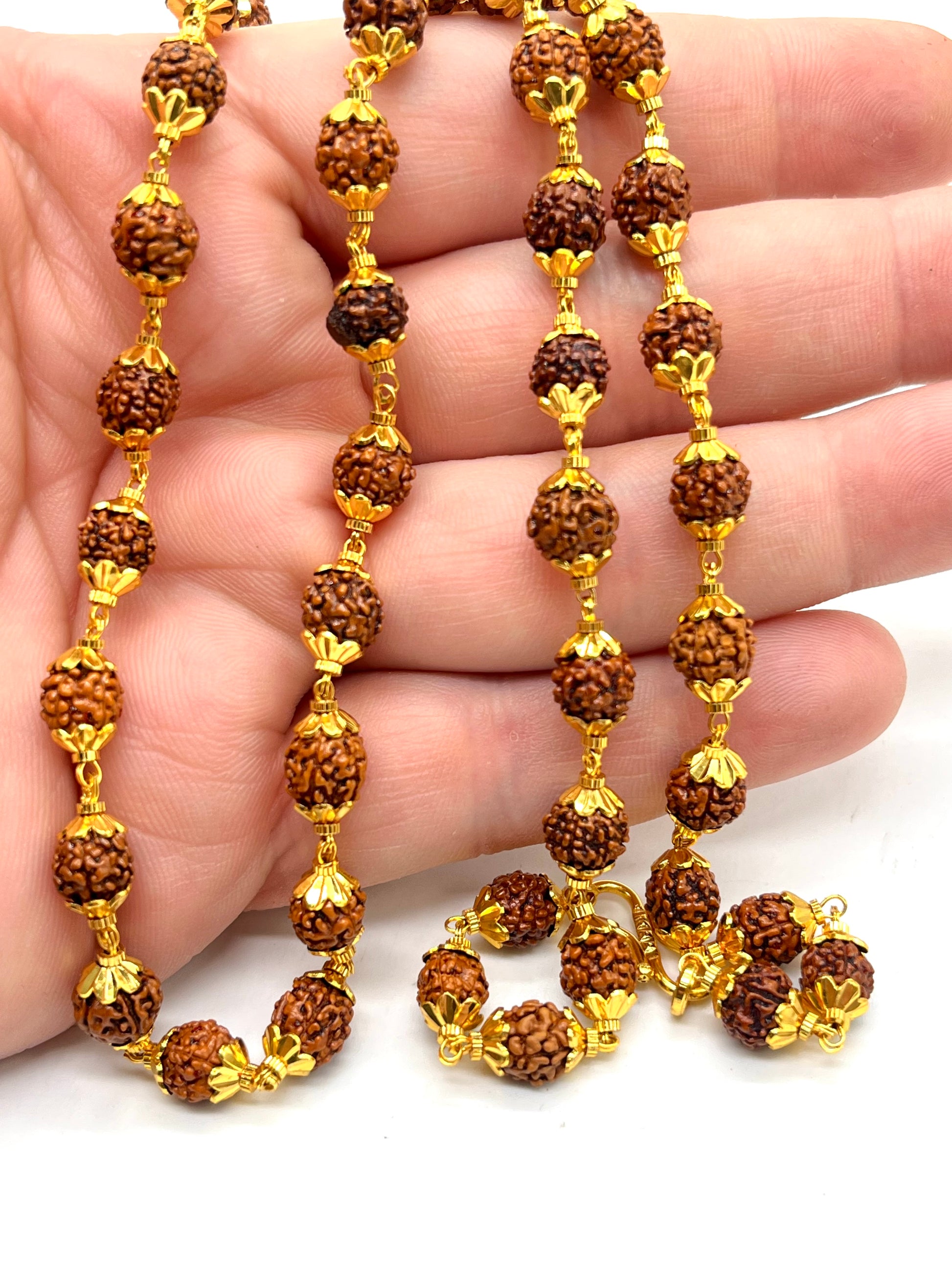 Gold and brown beaded necklace held in a hand against a white background