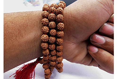 Close-up of a hand wearing a bracelet with brown beads and a red tassel.