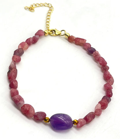Beaded bracelet with pink and purple stones and gold accents on a white background